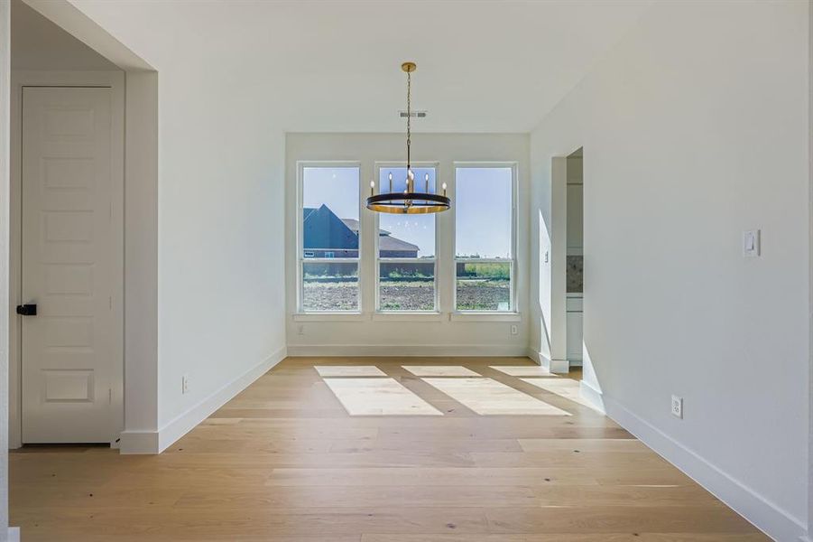 Unfurnished dining area featuring a chandelier and light wood-style flooring