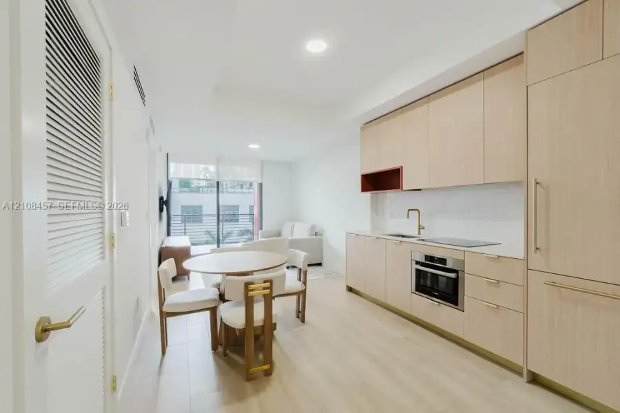 Kitchen featuring light wood-finish cabinetry, quartz countertops, an integrated refrigerator, recessed lighting, and wood-finish flooring Kitchen featuring light wood-finish cabinetry, quartz countertops, an integrated refrigerator, recessed lighting, and wood-finish flooring