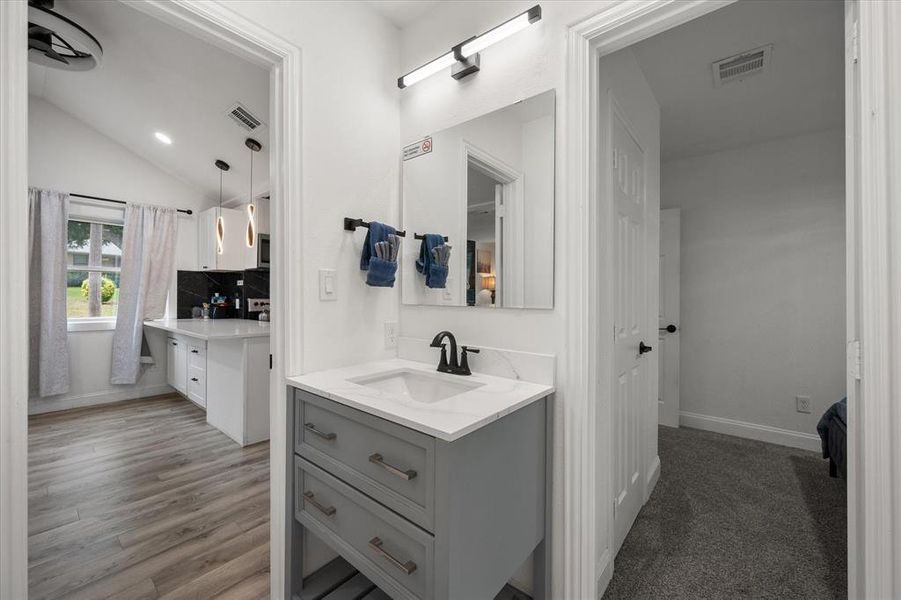 Bathroom featuring two vanities, vaulted ceiling, decorative backsplash, and wood finished floors Bathroom featuring two vanities, vaulted ceiling, decorative backsplash, and wood finished floors