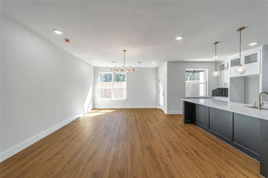 Kitchen with dark cabinetry, white cabinetry, decorative light fixtures, dark wood finished floors, and a chandelier Kitchen with dark cabinetry, white cabinetry, decorative light fixtures, dark wood finished floors, and a chandelier