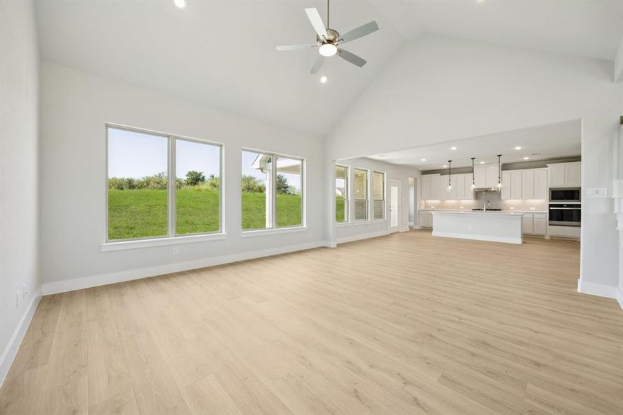 Unfurnished living room featuring high vaulted ceiling, recessed lighting, light wood finished floors, and a ceiling fan