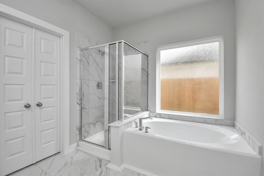 Escape to a spa-like oasis in this primary bathroom. Enjoy a walk-in shower with tile surround, a separate garden tub with custom detailing, and an elegant vanity featuring light countertops, and modern hardware. Experience luxury and relaxation in every detail