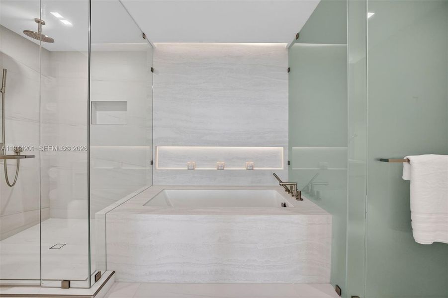 The 06 line primary bath feels like a private spa. Oversized and beautifully proportioned, it features a frameless glass walk in shower, designer soaking tub, dual vanities with stone counters, and sleek modern fixtures. Clean architectural lines, neutral luxury finishes, and generous storage for a calm, resort style retreat that complements the open coastal aesthetic of the residence.