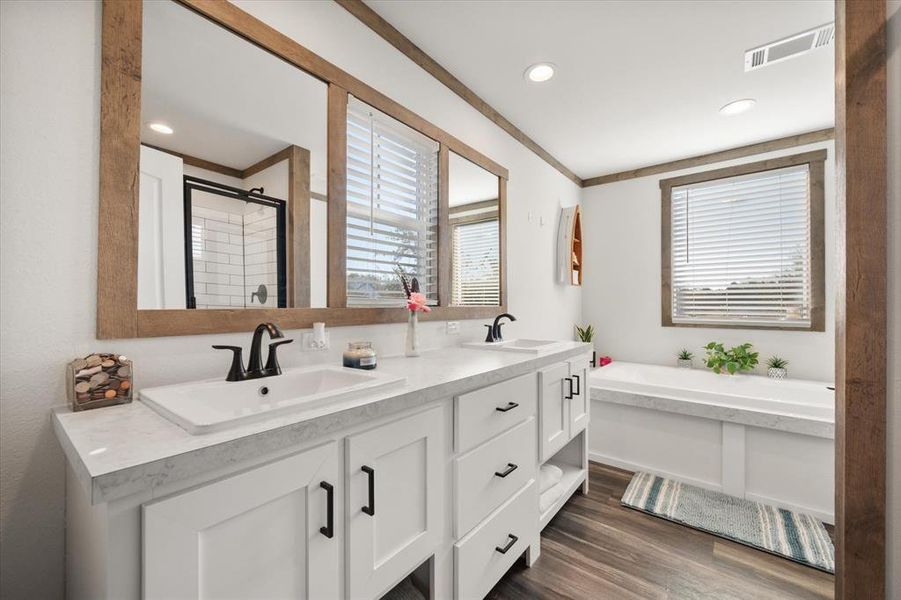 Bathroom with a bath, double vanity, a shower stall, dark wood-style flooring, and recessed lighting Bathroom with a bath, double vanity, a shower stall, dark wood-style flooring, and recessed lighting