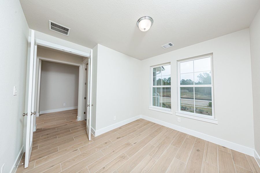 Tucked peacefully in the front of the home is this study, which features large windows, tile plank flooring, French doors, and neutral toned walls.
