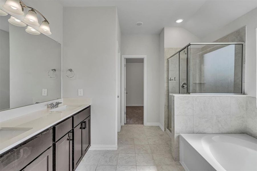 Bathroom featuring plus walk in shower, tile patterned flooring, and double sink vanity