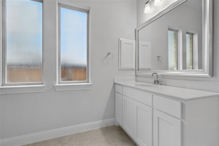 Bathroom featuring baseboards, vanity, and tile patterned floors Bathroom featuring baseboards, vanity, and tile patterned floors