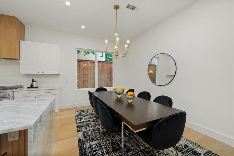 The property features an open-concept dining area with light wood flooring, a contemporary gold chandelier, and recessed lighting