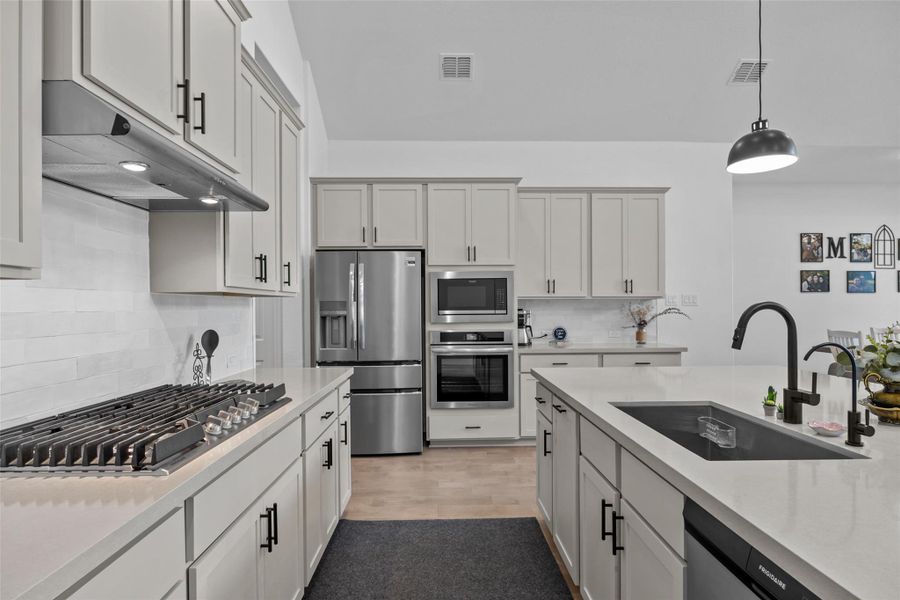 Gourmet kitchen features sleek white cabinetry, stainless steel appliances, and a central island with a modern sink. Gourmet kitchen features sleek white cabinetry, stainless steel appliances, and a central island with a modern sink.