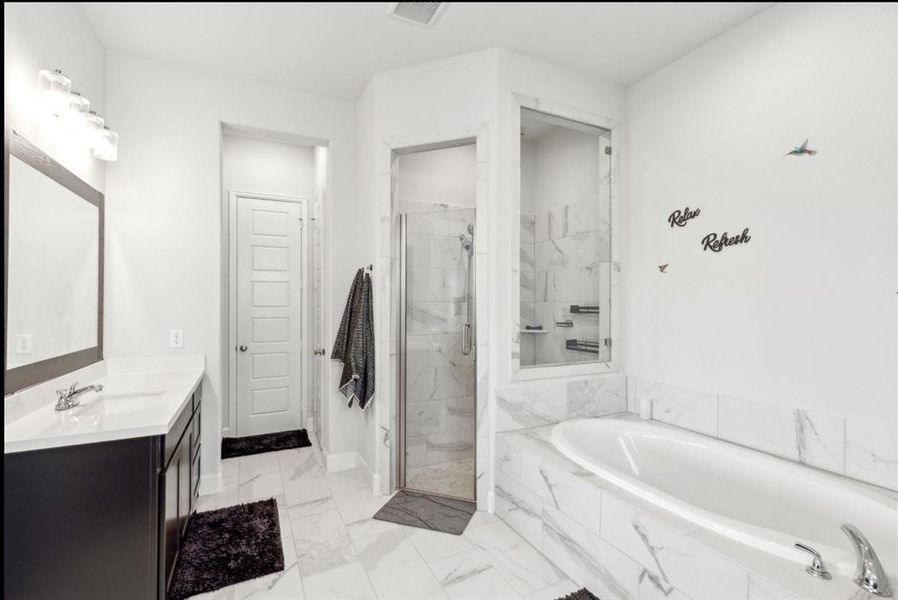 Bathroom featuring vanity, a bath, a shower stall, and light marble finish floors