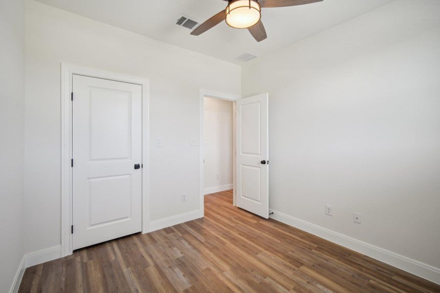 Bedroom 3 with a ceiling fan, wood finished floors, baseboards, and visible vents Bedroom 3 with a ceiling fan, wood finished floors, baseboards, and visible vents