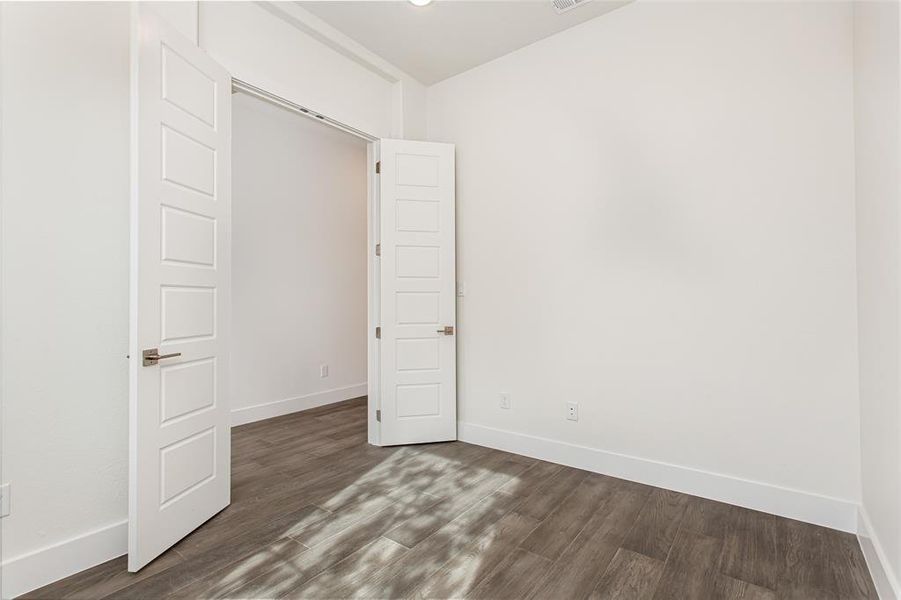 Unfurnished bedroom featuring dark hardwood / wood-style floors and a closet