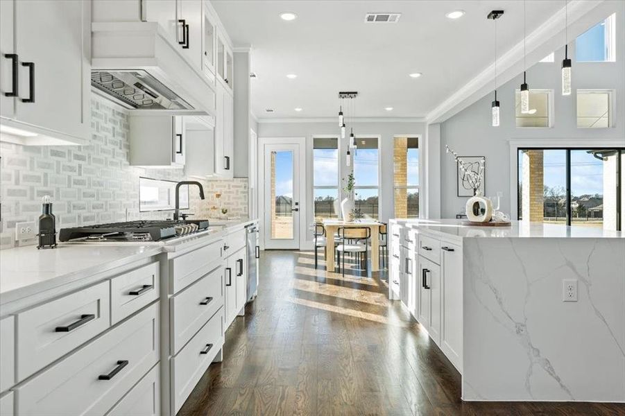 Kitchen featuring crown molding, decorative light fixtures, light stone countertops, and white cabinets