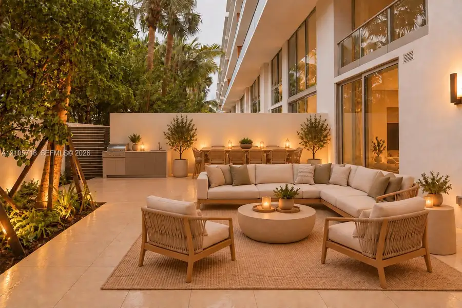 Private patio featuring stone tile flooring, a built-in outdoor kitchen with stainless steel grill, tall privacy walls, and full-height glass sliding doors