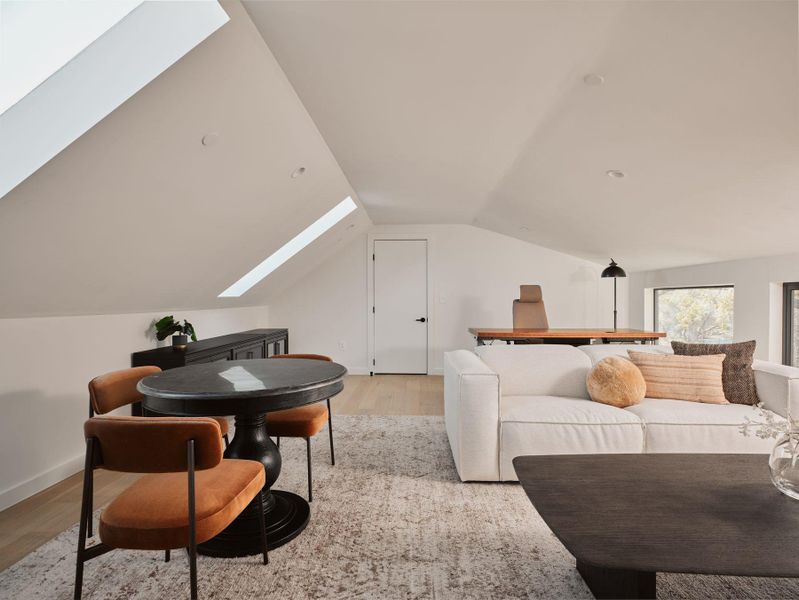 Bedroom with a skylight, light wood-style flooring, and vaulted ceiling