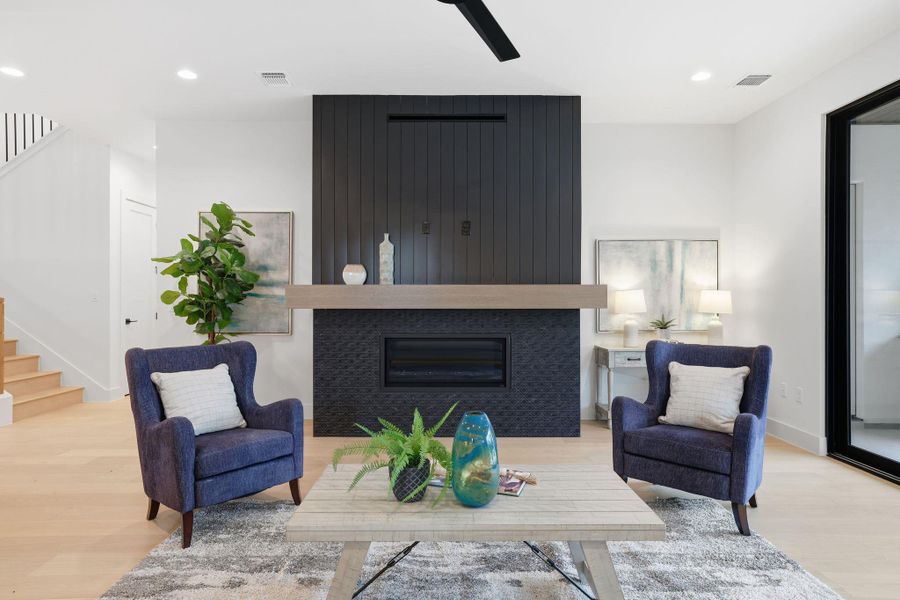 Living room with stairs, a large fireplace, wood finished floors, and recessed lighting
