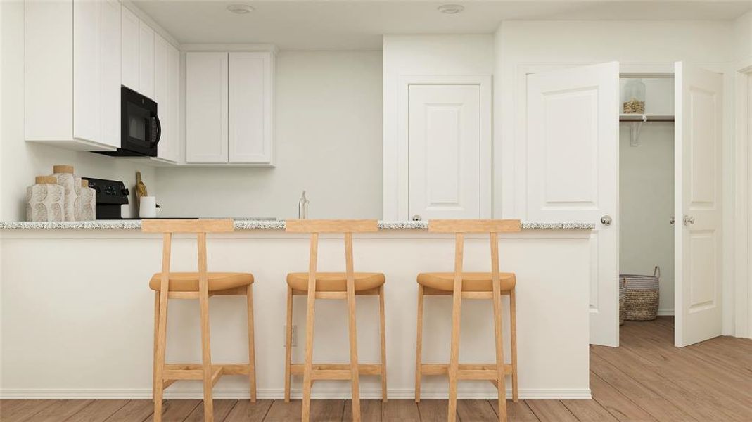 Kitchen featuring a breakfast bar area, light stone countertops, white cabinets, and light hardwood / wood-style floors