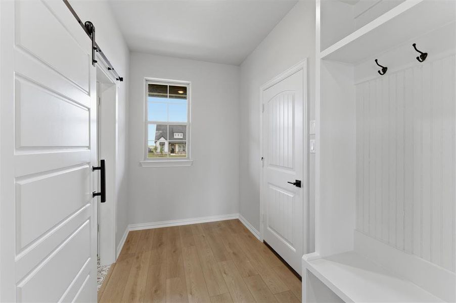 Mudroom with a barn door and light wood-style floors