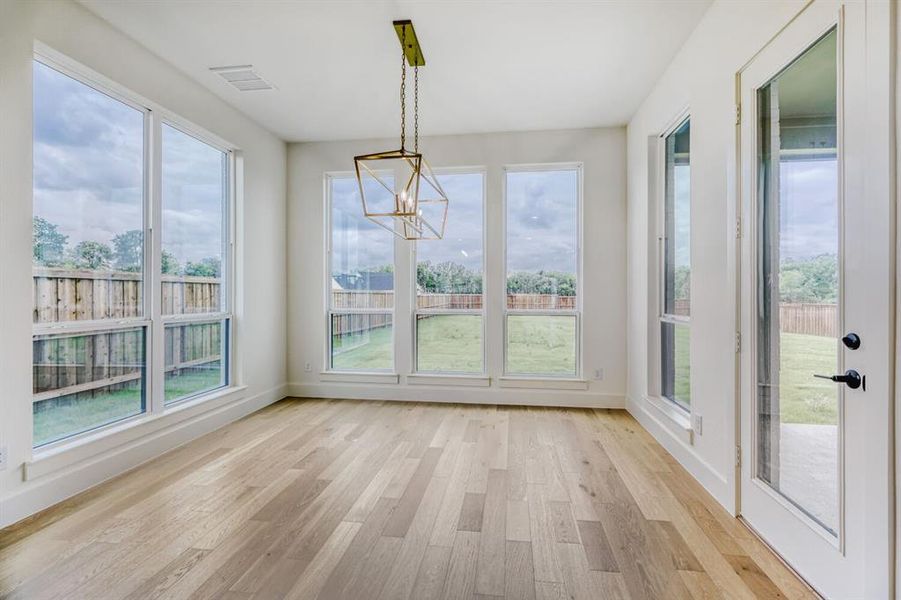 Unfurnished dining area with light wood-style floors, a chandelier, and plenty of natural light