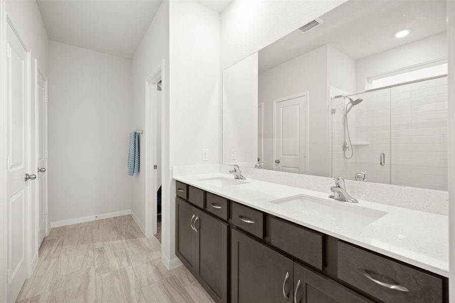 The ensuite bath combines comfort and functionality with a well-designed layout. Dual sinks provide convenience and ample counter space for daily routines. The ensuite bath combines comfort and functionality with a well-designed layout. Dual sinks provide convenience and ample counter space for daily routines.