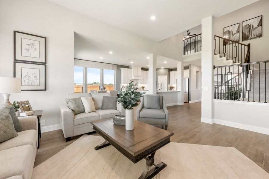 Open-concept living room with hardwood floors, neutral furniture, and staircase leading to second floor loft area