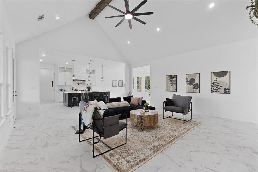 Open-concept interior featuring vaulted ceilings with an exposed wood beam, large format tile flooring, and recessed lighting