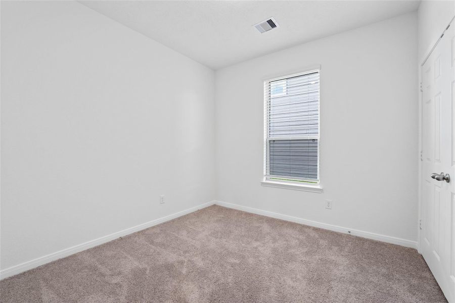 This secondary bedroom offers comfort and style with plush carpeting, neutral paint tones, recessed lighting, a large window with blinds, and a generously sized closet.