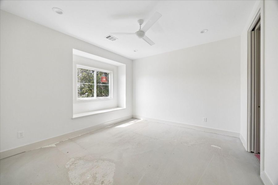 Light filled secondary bedroom featuring a charming window nook that adds architectural interest and a cozy touch to the space. The bright, neutral finishes and clean lines create a fresh, airy feel, while the well proportioned layout allows for flexible furniture arrangements. Ideal as a guest room, secondary bedroom, or home office with plenty of natural light throughout the day.