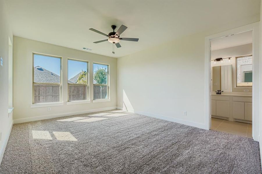 Unfurnished bedroom with light carpet, ceiling fan, and ensuite bathroom
