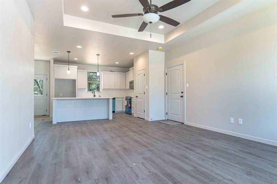 Kitchen featuring a tray ceiling, open floor plan, white cabinets, light countertops, and recessed lighting