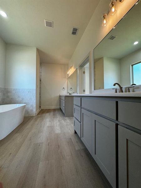 Bathroom with hardwood / wood-style floors, a bath, and vanity