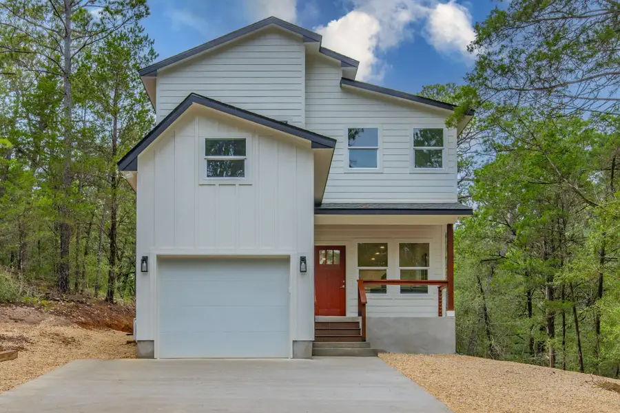 Modern two-story residence with a contrasting red entry door, surrounded by natural woodland. Modern two-story residence with a contrasting red entry door, surrounded by natural woodland.