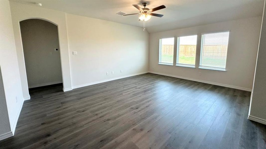 Spare room featuring arched walkways, dark wood finished floors, ceiling fan, and vaulted ceiling