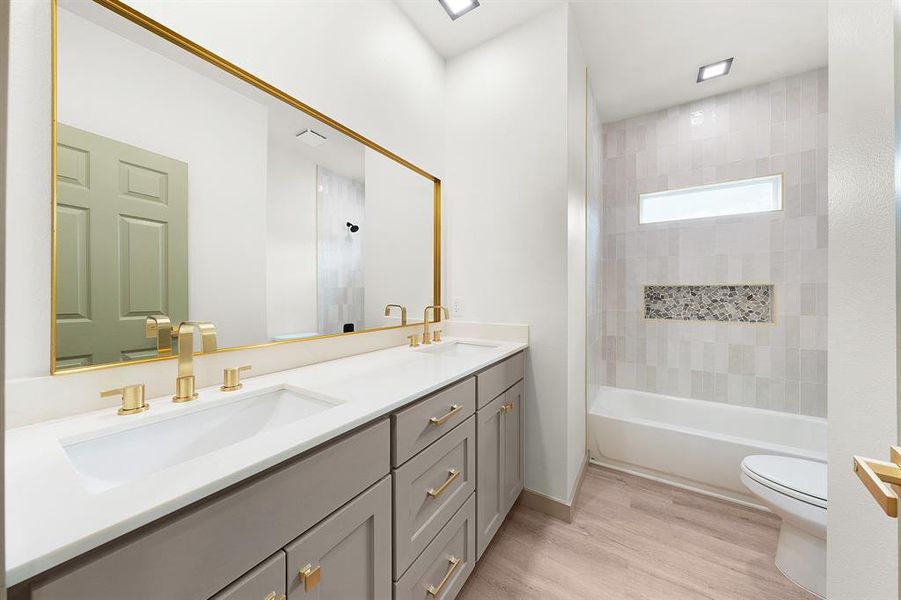 Full bath with double vanity, toilet, a sink, and wood finished floors