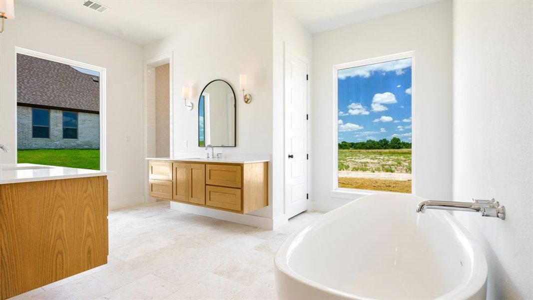 Bathroom with a wealth of natural light, tile flooring, vanity, and a bath