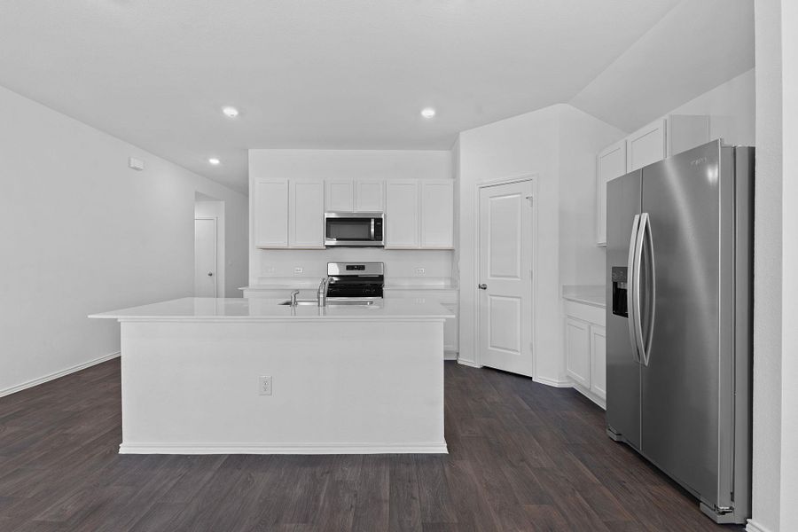 Kitchen featuring dark wood-style floors, stainless steel appliances, light countertops, and white cabinetry