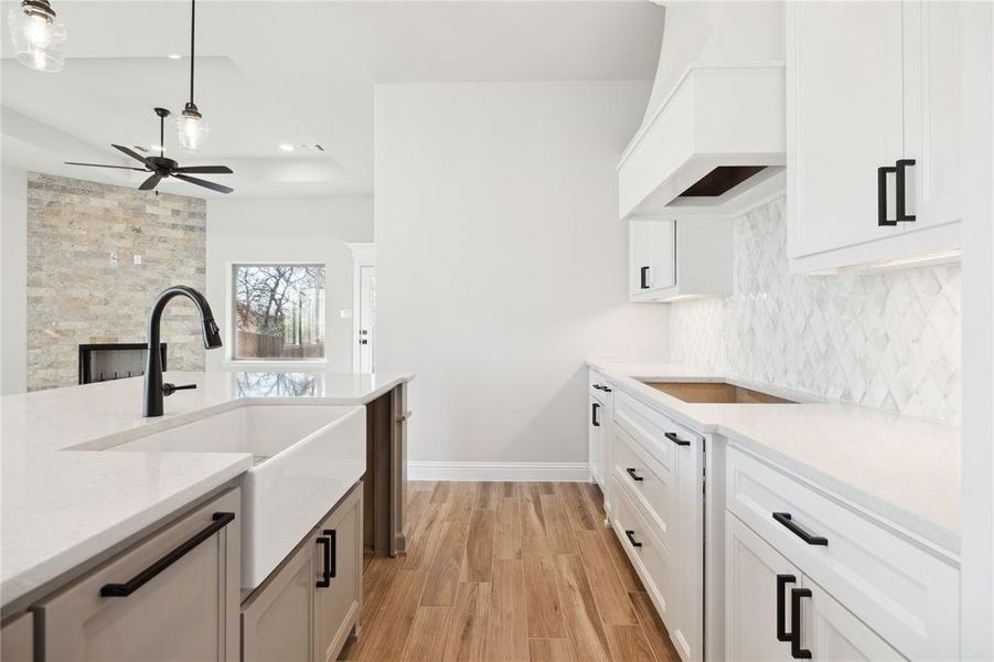 Kitchen featuring white cabinets, pendant lighting, and premium range hood