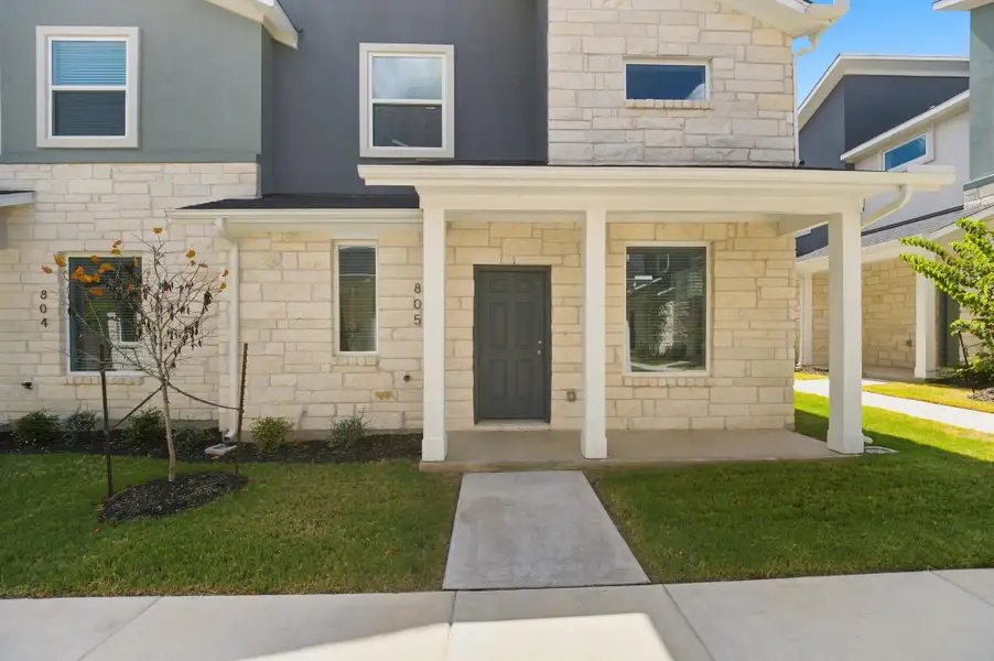 Limestone and smooth siding compose a modern facade with a covered concrete entry porch.