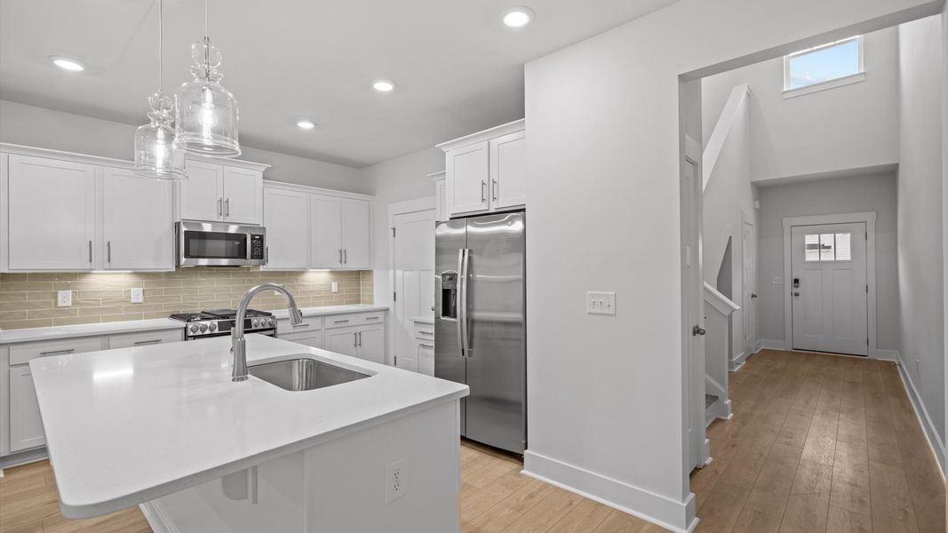 Superior kitchen with quartz countertops, pendant lighting, and a generously sized island