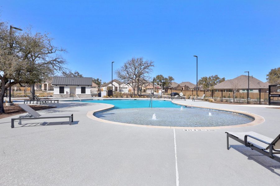 Community pool with a patio, fence, and a residential view