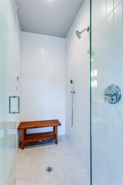 Bathroom featuring tiled shower, tile walls, and tile patterned floors