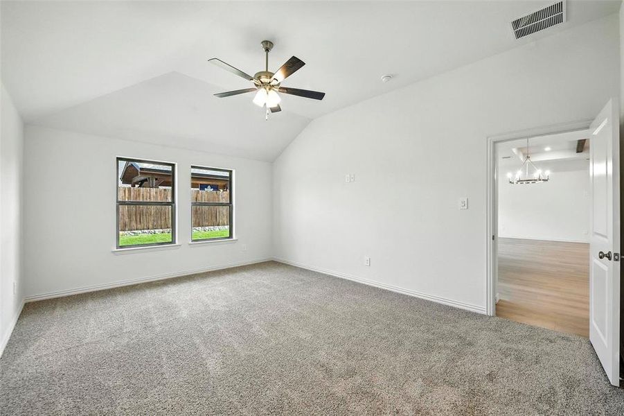 Empty room featuring carpet floors, lofted ceiling, a ceiling fan, and a chandelier