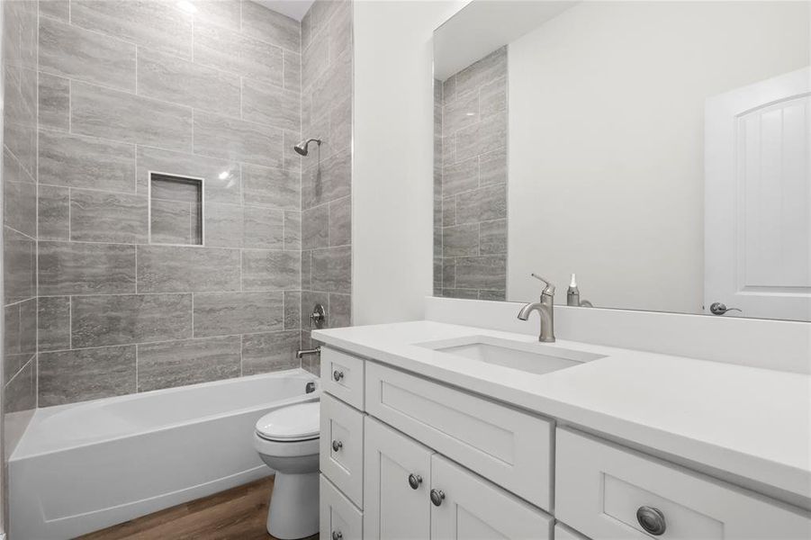 Full bathroom featuring hardwood / wood-style flooring, vanity, toilet, and tiled shower / bath