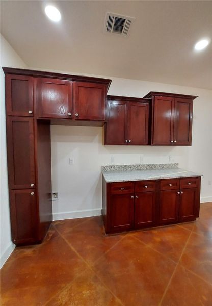 Kitchen with bold wood finish cabinetry, concrete floors, and recessed lighting