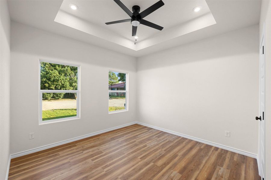 Empty room featuring wood finished floors, a raised ceiling, recessed lighting, and ceiling fan Empty room featuring wood finished floors, a raised ceiling, recessed lighting, and ceiling fan