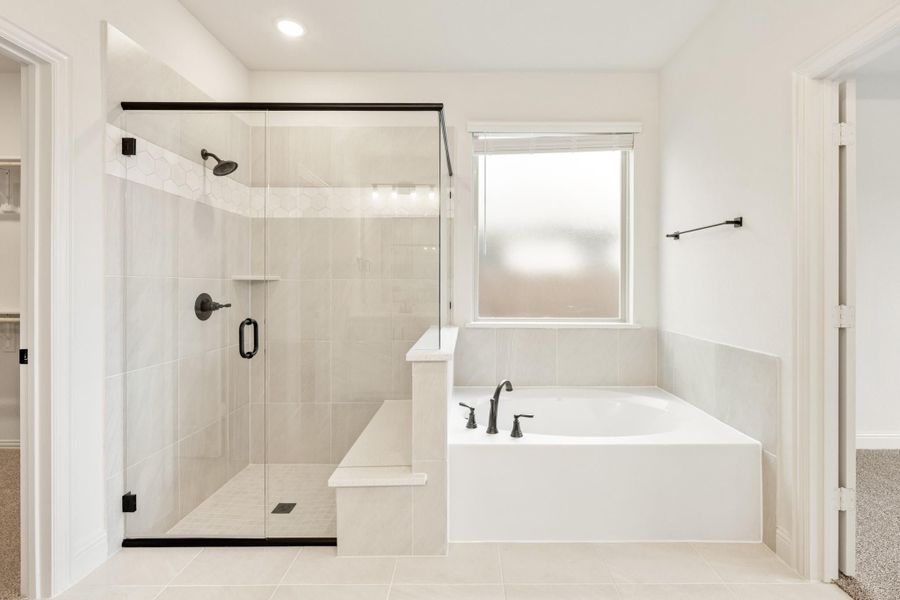 White bathroom with glass-enclosed walk-in shower, soaking tub, and black hardware fixtures White bathroom with glass-enclosed walk-in shower, soaking tub, and black hardware fixtures