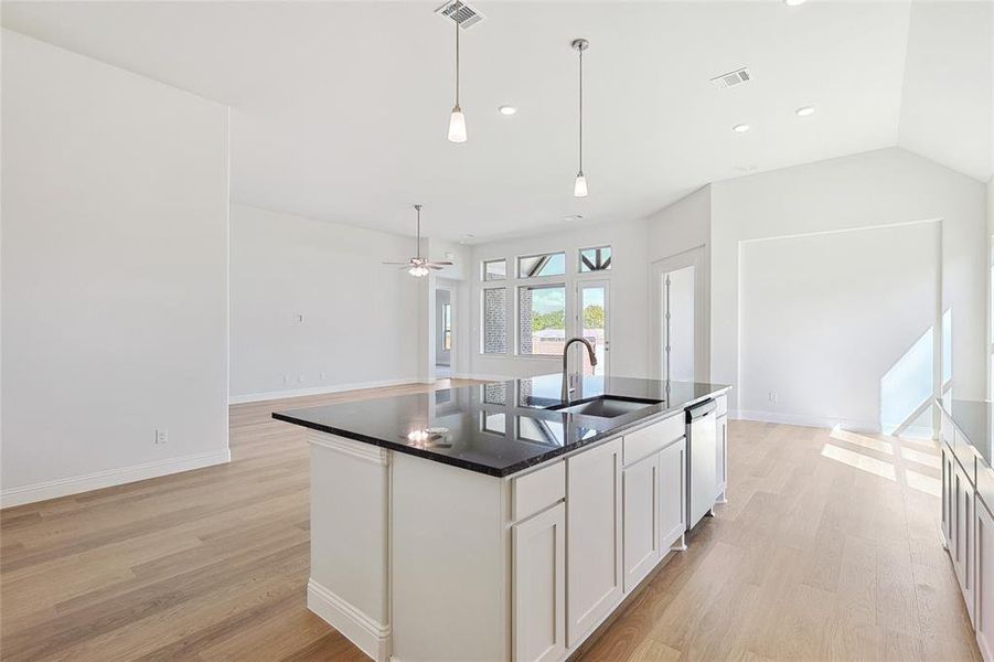 Kitchen with light hardwood / wood-style flooring, white cabinets, dishwasher, sink, and a center island with sink