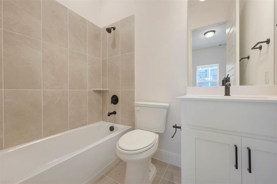 Bathroom featuring a white bathtub, light-toned tile surround with a built-in niche, and matte black plumbing fixtures