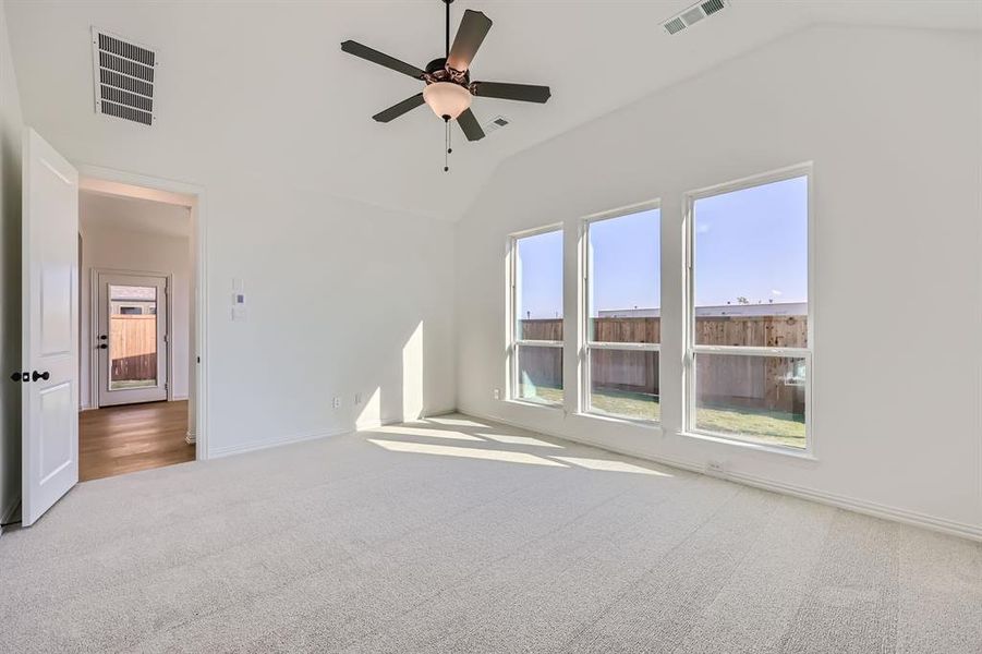 Carpeted empty room with lofted ceiling and ceiling fan