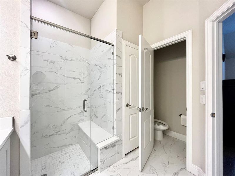 Bathroom featuring tile patterned flooring, an enclosed shower, toilet, and vanity